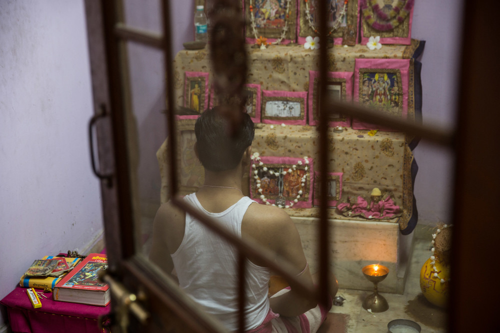 A Hindu man prays in his home temple. Each Hindu family has a private temple in their home, ranging from a small shelf to an elaborate prayer room.