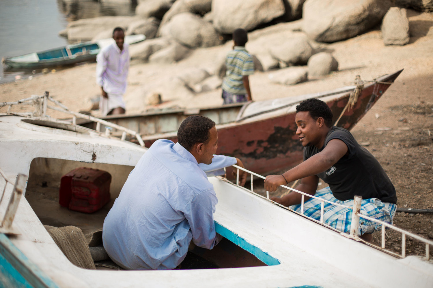  Young men repair the siding of a boat on the Nile river bank on Heisa Island. 