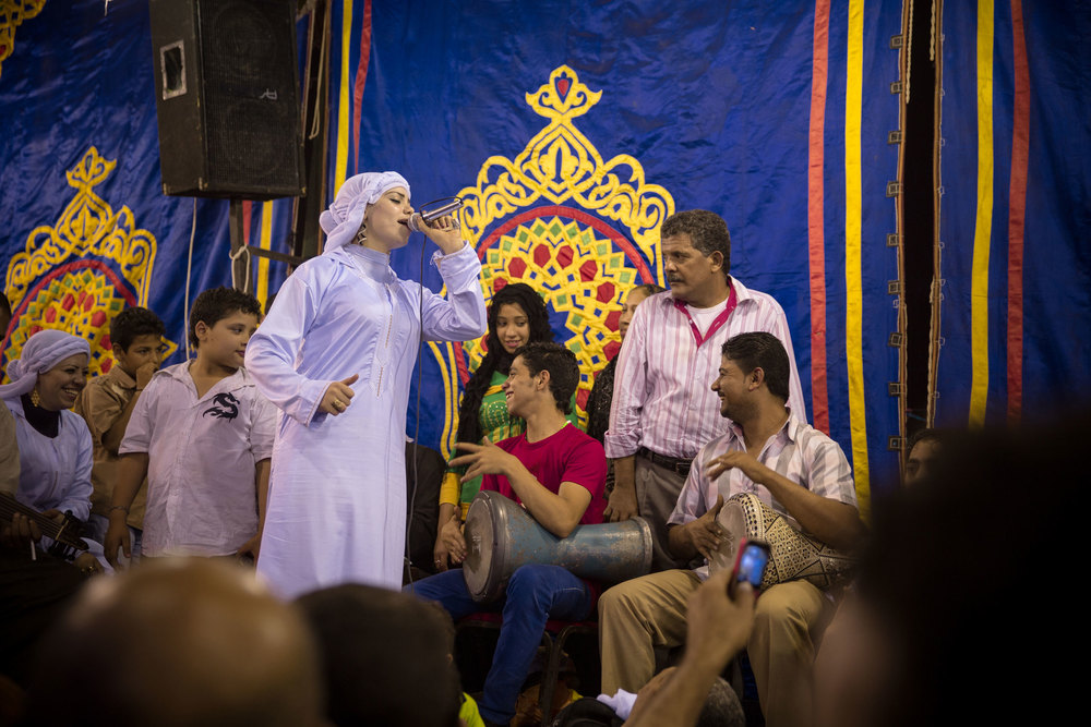 Some of the only female moulid singers in Egypt perform for a large crowd. They are part of a family act, their male relatives play the instruments.